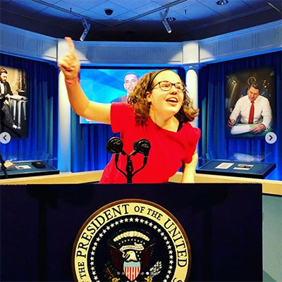 From Illinois to the White House exhibit. A teenage girl stands at a mock President of the United State podium, pretending to make a speech.